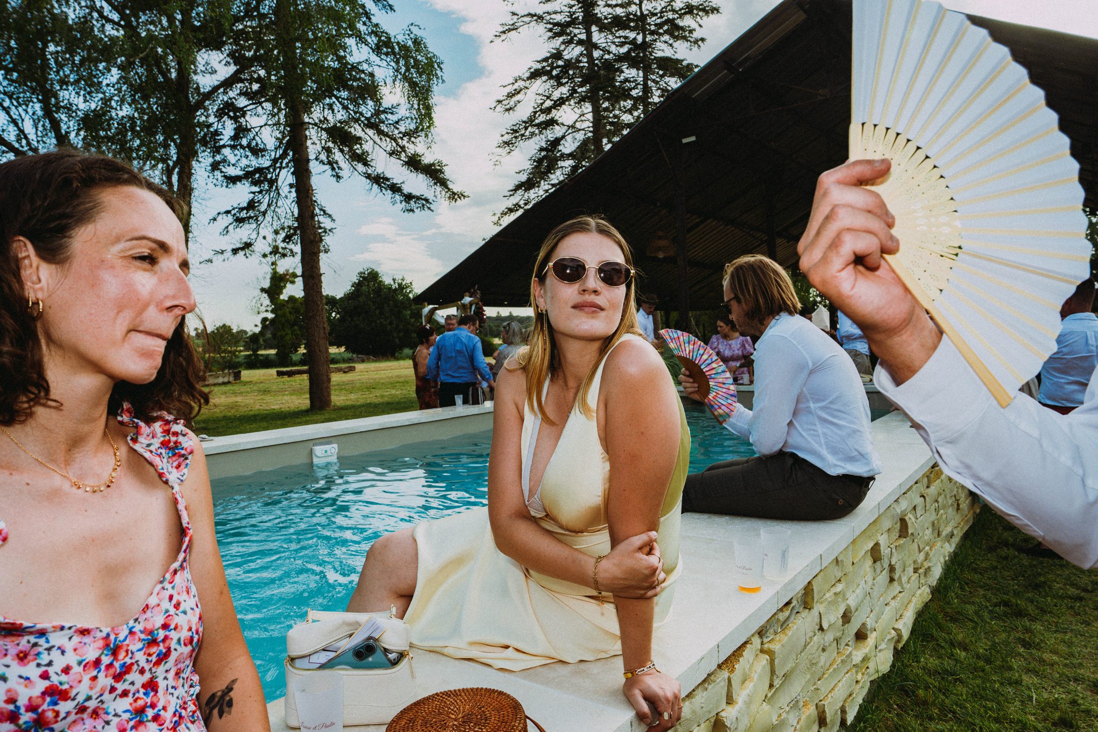 Une invitée assise au bord de la piscine pendant le vin d'honneur