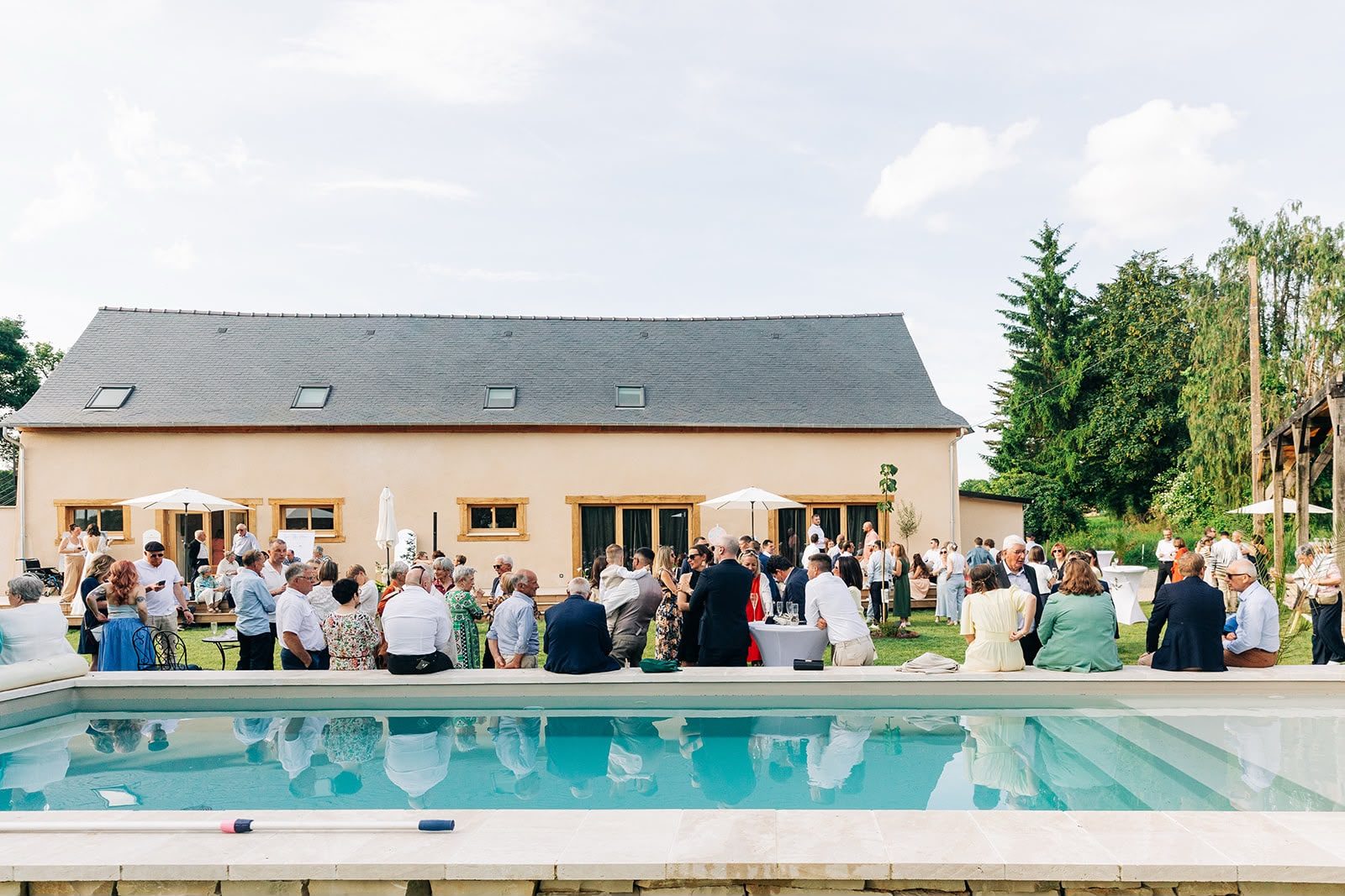Les invités réunis devant la maison, au bord de la piscine