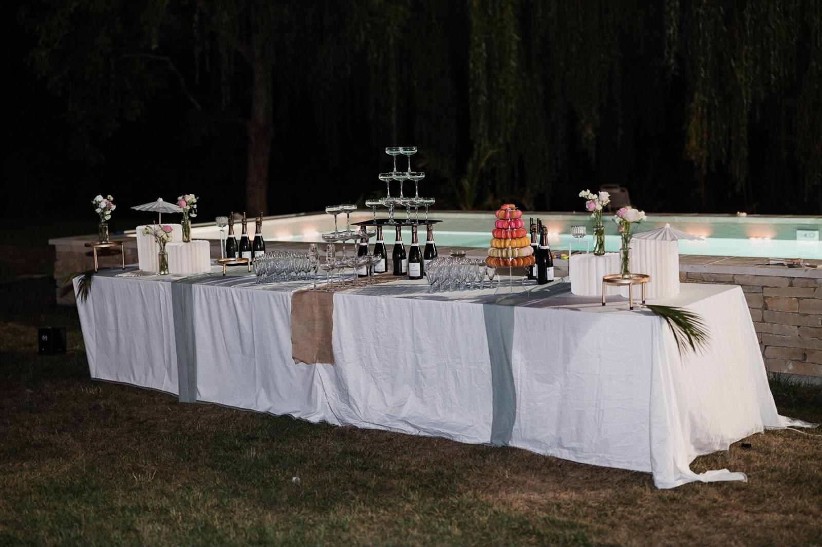 Le buffet et la pyramide de coupes dressés devant la piscine illuminée, le soir